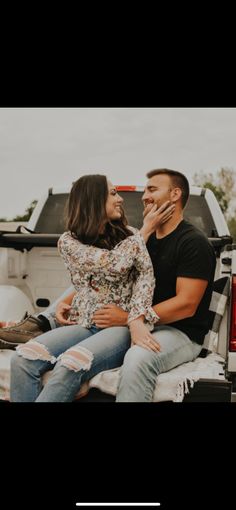 a man and woman sitting on the back of a truck