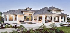 a large white house with a pool in the front yard and landscaping around it at dusk