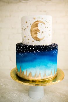 a three tiered cake with blue and white frosting, gold stars and a crescent on top