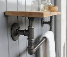 an industrial style pipe and wooden shelf with soap dispenser on the wall