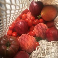 some tomatoes and other fruits are in a netted bag on the table or floor