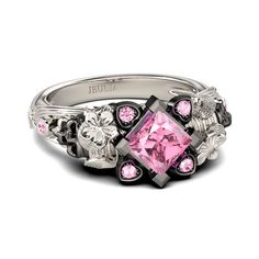 a pink diamond ring with skulls on the sides and flowers in the middle, surrounded by black diamonds