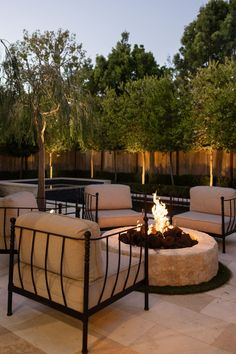 an outdoor fire pit surrounded by chairs and tables