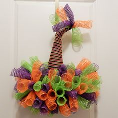 an orange, green and purple wreath hanging on a door