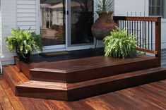 a wooden deck with potted plants on it and an open door to the outside