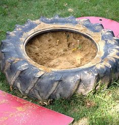 an old tire sitting in the grass next to a pink board and some other items