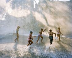 children playing in water sprinkles at the park on a hot summer day