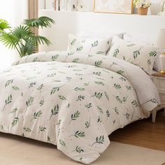 a bed with green leaves on it in a room next to a potted plant