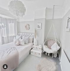 a white bedroom with a hammock hanging from the ceiling and pillows on the bed