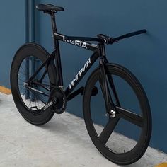 a black bike parked next to a blue wall