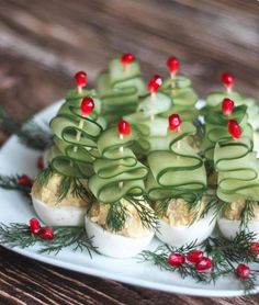 an arrangement of deviled eggs with cucumbers and cherries on a plate