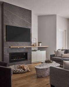 a living room with grey couches and a flat screen tv mounted on the wall