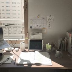 an office desk with a laptop computer, notebook and coffee cup on top of it