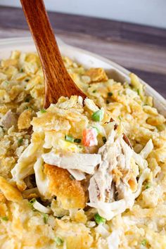 a wooden spoon is in a casserole dish filled with chicken and rice salad