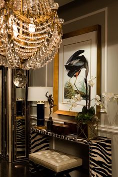 a living room with zebra print furniture and a chandelier hanging from the ceiling