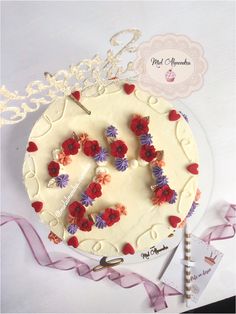 a cake decorated with flowers and the letter e on it is next to a pink ribbon