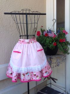 a pink dress on display next to a potted plant with red flowers in it