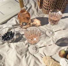 the table is set with wine glasses and fruit