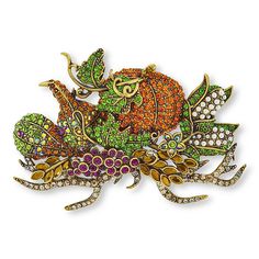 a brooch with an orange and green frog on it's back, surrounded by jewels