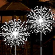 two white firework lights sitting on top of a metal pole next to each other