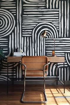 a chair sitting in front of a desk with a lamp on top of it next to a black and white wall