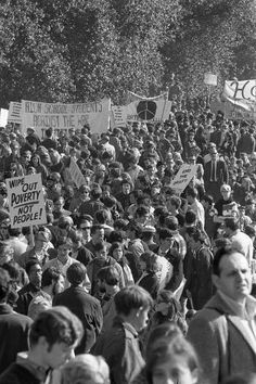 a large group of people holding signs and standing in the middle of a street with trees