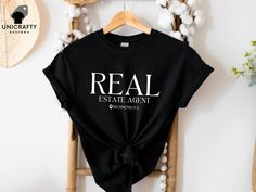 Elevate your real estate game with our Custom Real Estate Agent T-shirt. This personalized real estate tee, featuring your custom location, is the perfect gift for any dedicated realtor. Ideal for agent marketing attire, it combines professionalism and style, making it a must-have for your wardrobe. See more of our designs in our REAL ESTATE section: https://www.etsy.com/shop/unicraftydesigns/?etsrc=sdt&section_id=49847464 CHECK OUT MORE FOR OUR UNIQUE DESIGNS: unicraftydesigns.etsy.com SIZE & MATERIAL * Unisex T-shirt * Runs true to size * 100% cotton (fibre content may vary for different colours) HOW TO ORDER: *Please make sure to check all photos in the listing. *Choose your shirt colour and size. *Click add to cart. You can follow the same steps to add more items in your cart. *Click " Real Estate Shirts, Shirt Colour, Realtor Gifts, Estate Agent, Real Estate Agent, Shirt Design, Custom Shirts, Unisex T Shirt, Gender Neutral