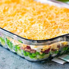 a casserole dish with cheese, peas and ham in it on a table