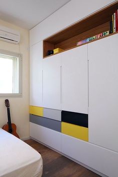 a bedroom with a bed, bookshelf and white cupboards