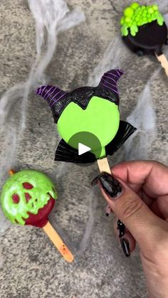 a hand holding an apple and two halloween pops