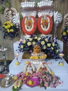 a table topped with flowers and candles next to a buddha statue on top of a white table