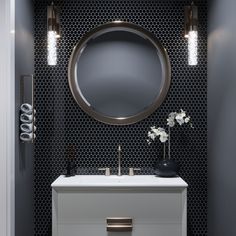 a bathroom vanity with a round mirror above it and two flowers on the counter top