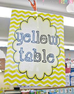 a sign that says yellow table hanging from the ceiling in front of bookshelves