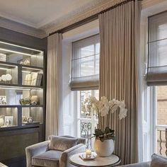 a living room filled with furniture and windows covered in draping next to a fire place