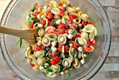 a bowl filled with pasta and vegetables on top of a wooden table