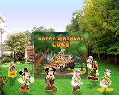 a group of mickey mouses standing in front of a happy birthday sign on the grass