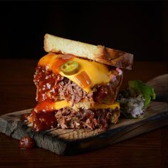 a sandwich with meat, cheese and lettuce on a cutting board