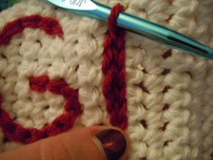 the crochet is being worked on by someone using a knitting needle to stitch