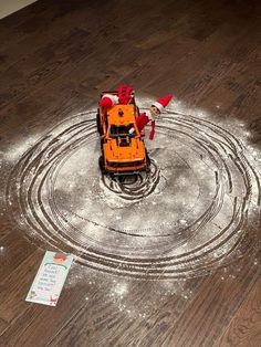 a toy truck is sitting in the middle of a circle with snow on it's floor