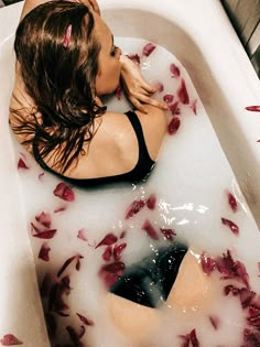 a woman in a bathtub with rose petals on the floor