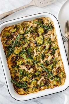 a casserole dish with broccoli, mushrooms and herbs in it on a table