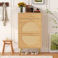 a wooden cabinet sitting in front of a wall with pictures and flowers on top of it