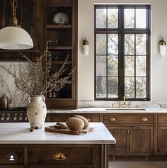 a large kitchen with wooden cabinets and marble counter tops, along with a vase filled with flowers