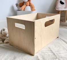 a wooden toy box sitting on top of a bed next to a stuffed animal bear