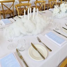 the table is set with white linens, silverware and napkins on it