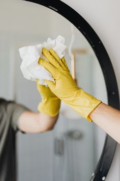 a man in yellow gloves wiping his face with a cloth and cleaning the bathroom mirror