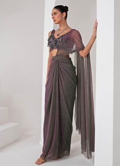 Elevate your style with the exquisite Lavender Pre Draped Crepe Saree, meticulously crafted from a luxurious platinoir crepe. The lavender saree shimmers with a subtle metallic tone, adding a touch of contemporary elegance to the traditional silhouette. Paired with a sleeveless V-neck blouse, this ensemble showcases intricate tonal crystal tassel and cutdana embellishments, creating a perfect blend of modern flair and classic grace. The pre-draped design ensures effortless wear, making it an ideal choice for those who desire both sophistication and convenience. Whether you're attending a Cocktails, Sangeet nights or a glamorous evening event, this saree promises to make a statement, reflecting your impeccable taste and style. Composition : Blouse - Crepe blend, Saree - Platinoir Crepe Care Lavender Saree, Draped Saree, Crepe Saree, Drape Saree, Purple Metallic, Indian Wedding Wear, Western Design, Designer Drapes, Blouse For Women