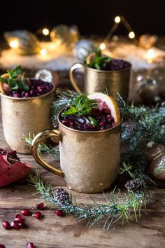 two gold mugs filled with cranberry punch and garnished with greenery