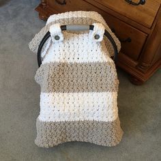 a crocheted bag sitting on the floor next to a dresser with drawers in it