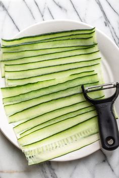 a white plate topped with sliced cucumbers and a black handled shear